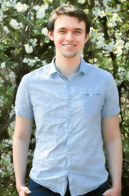 Justin smiling in front of a tree